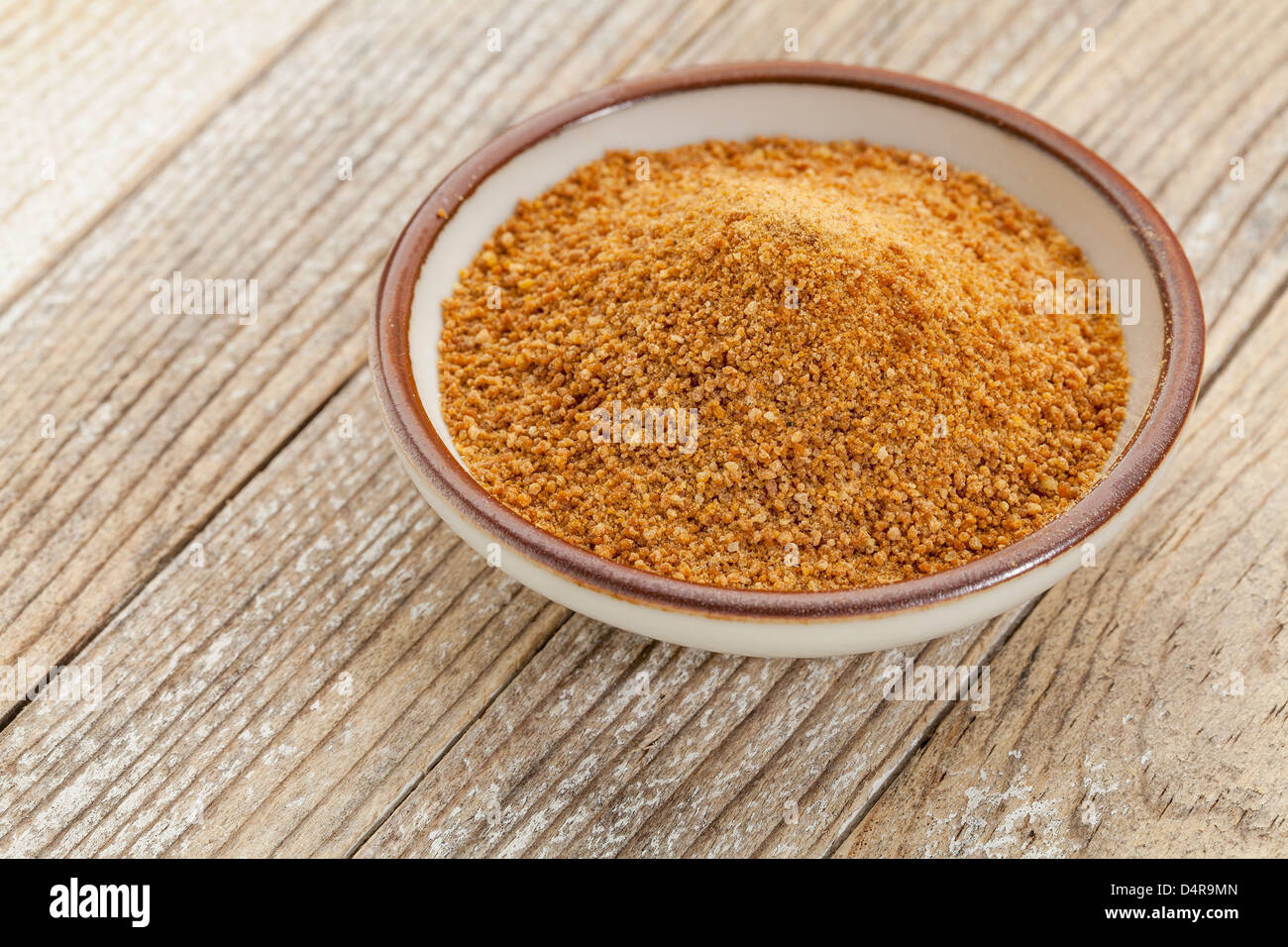 Piccolo vaso in ceramica degli oli di noce di cocco zucchero palm contro un dipinto di bianco di grunge Sfondo legno Foto Stock