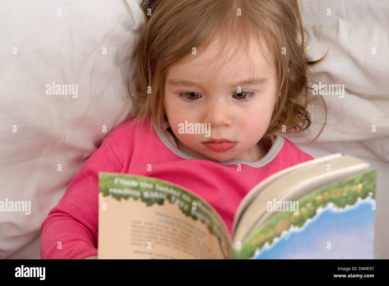 Carino il Toddler leggendo le sue storie prima di lei va a dormire. Abitudini di lettura inizia con età precoce. Foto Stock