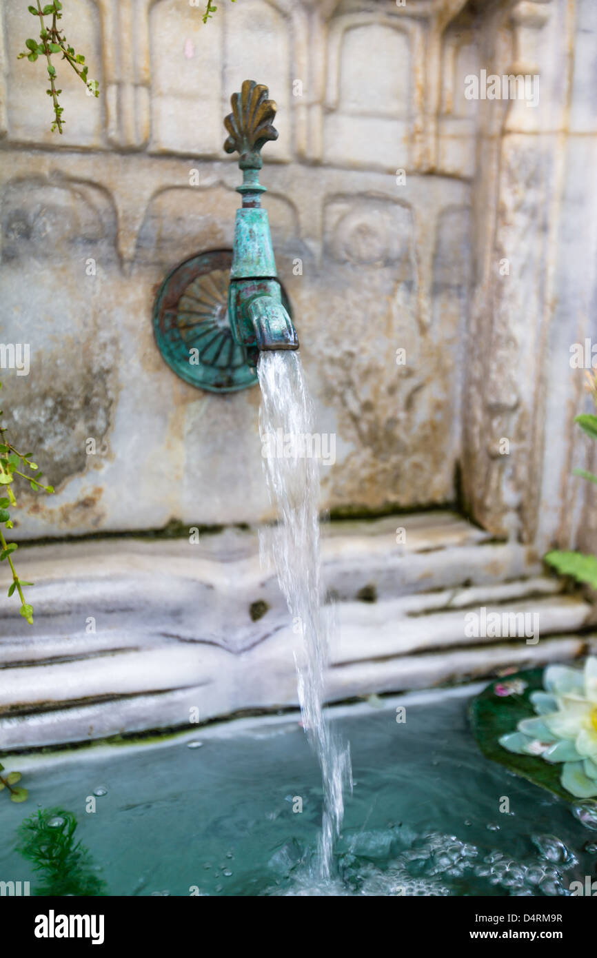 Vecchia fontana in marmo con rubinetto di ottone ancora versare dell'acqua. Foto Stock
