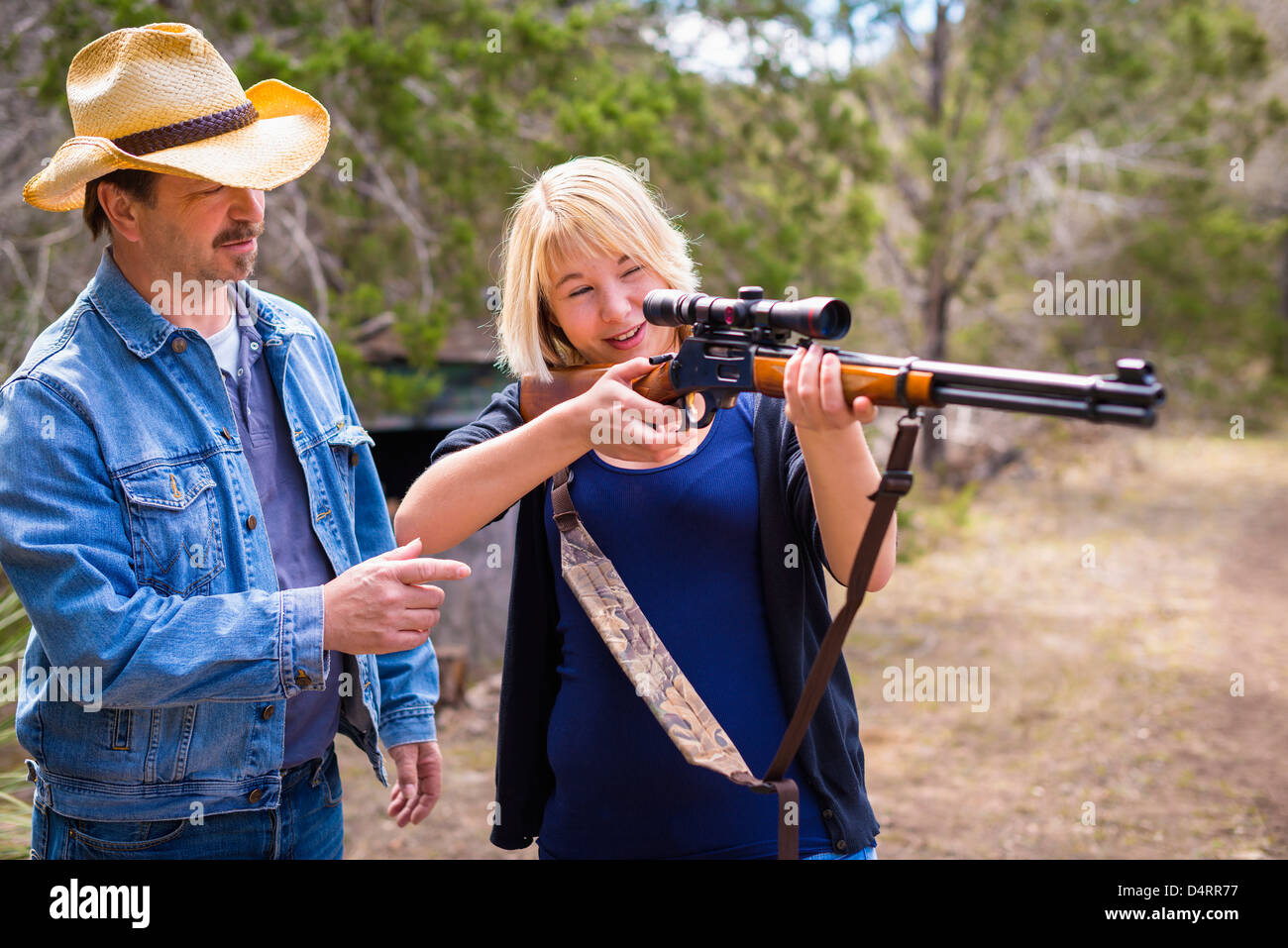 Padre ad insegnare la sua figlia come per sparare con un fucile da caccia di arma da fuoco Foto Stock