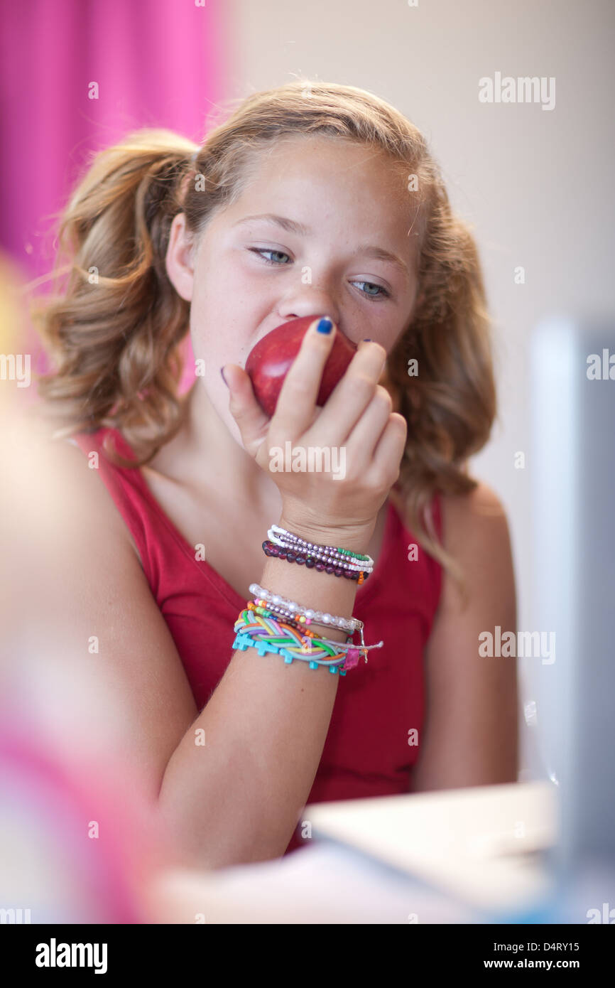 Ragazza mangiare apple al desk Foto Stock