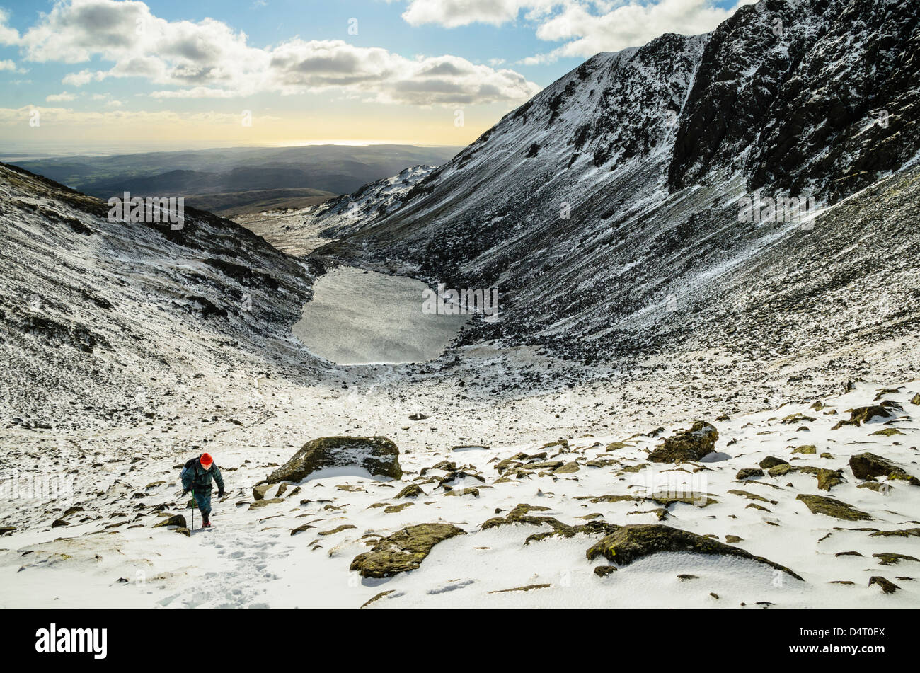 Walker in neve capre sopra acqua in Coniston Fells del Distretto del Lago con Dow roccioso sulla destra Foto Stock