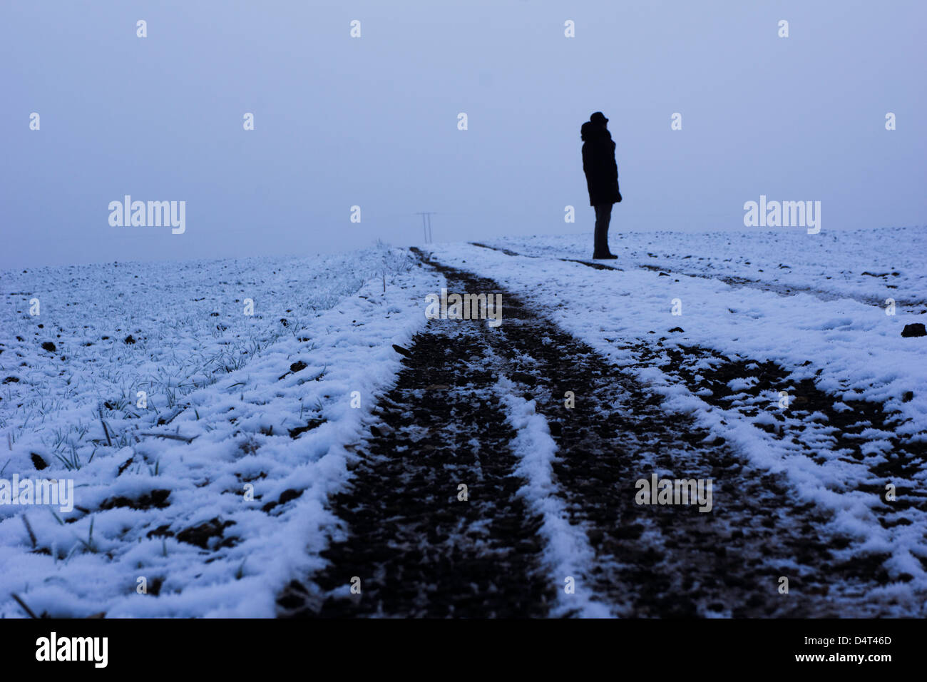Scene invernali intorno a Doncaster con una casa di pietra ricoperta di neve, una persona che cammina attraverso un sentiero boschivo ghiacciato e impronte attraverso il fiel innevato Foto Stock