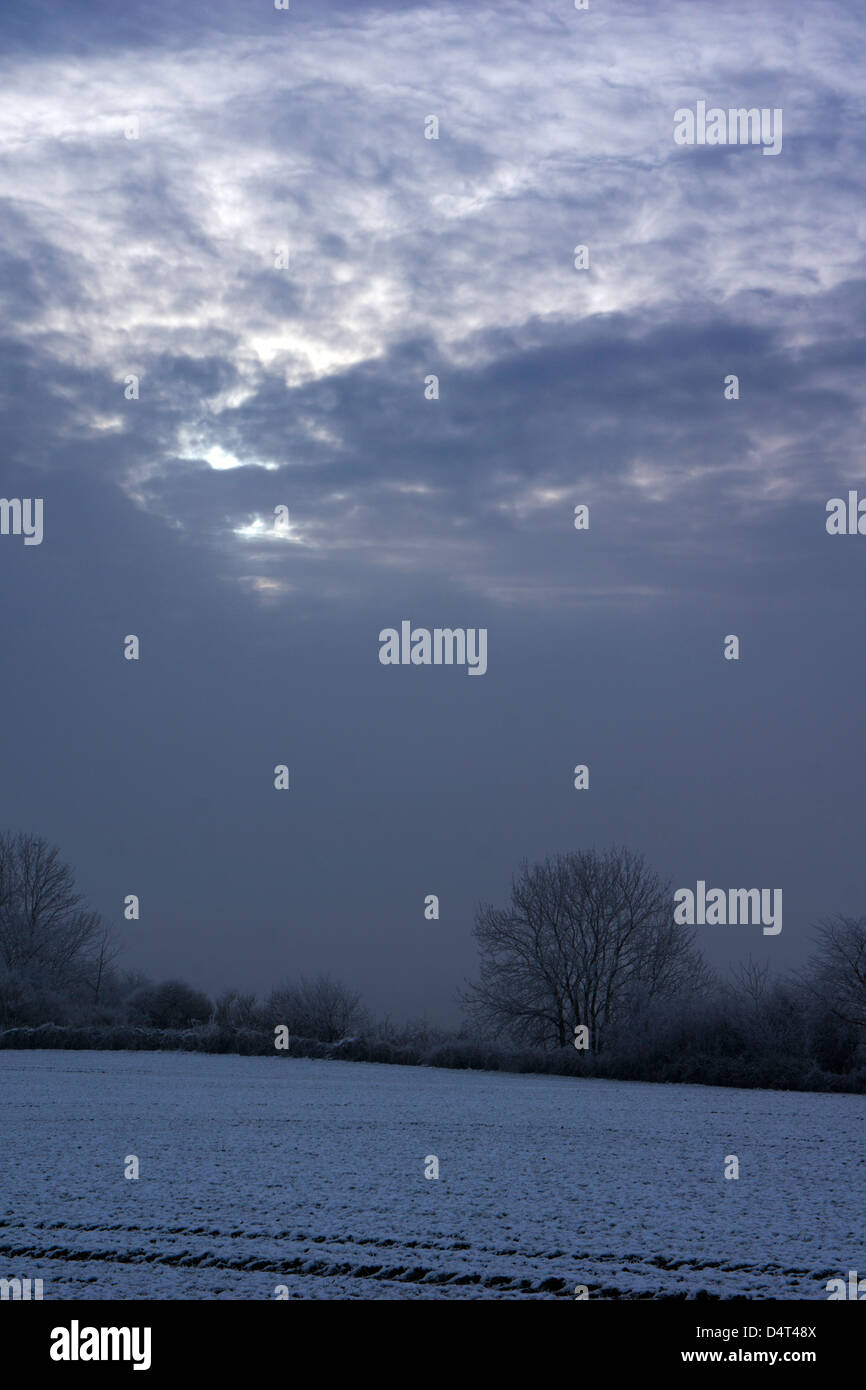 Scene invernali intorno a Doncaster con una casa di pietra ricoperta di neve, una persona che cammina attraverso un sentiero boschivo ghiacciato e impronte attraverso il fiel innevato Foto Stock