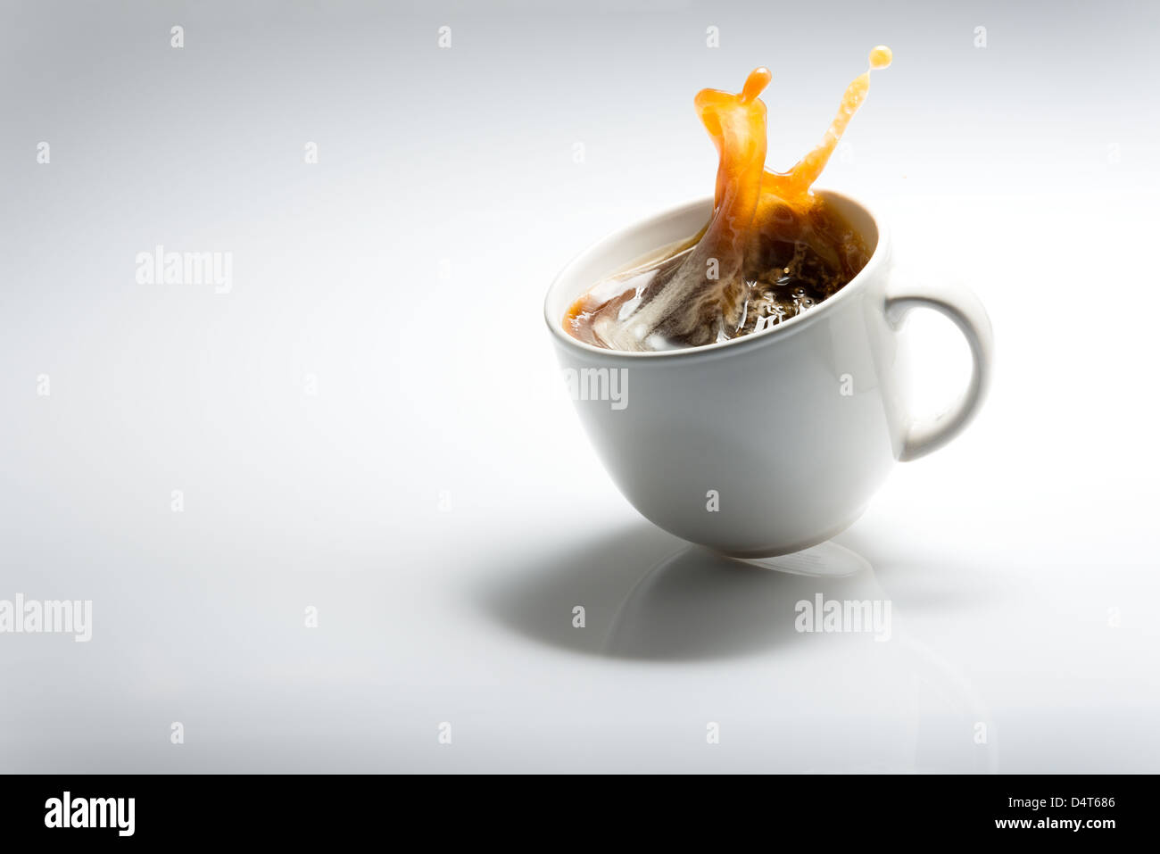La caduta di tazza di caffè contro uno sfondo bianco Foto Stock
