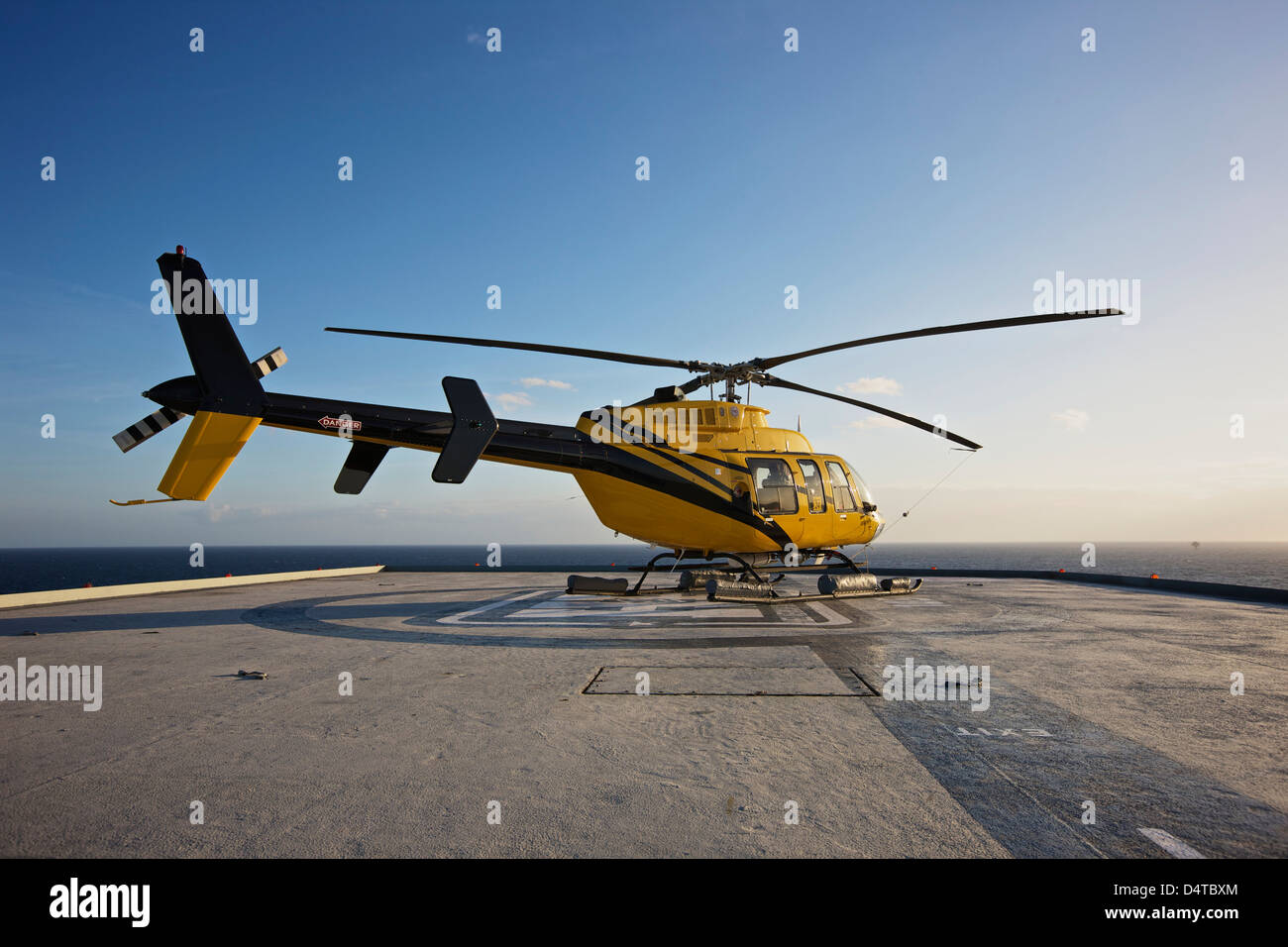 Una campana 407 elicottero utility su elisuperficie di un impianto di trivellazione petrolifera. Foto Stock