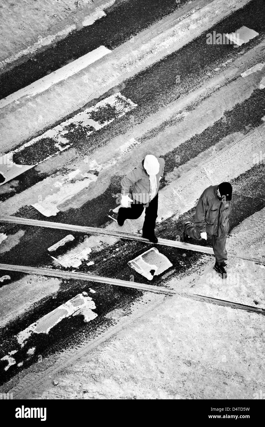 Due persone che attraversano la strada su una via pedonale di attraversamento in inverno Foto Stock