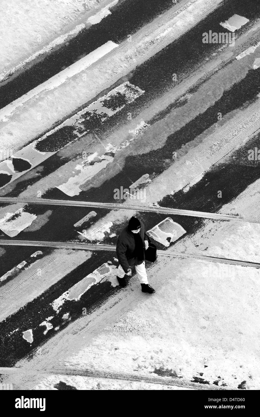 Donna che attraversa la strada a un percorso pedonale di attraversamento in inverno Foto Stock