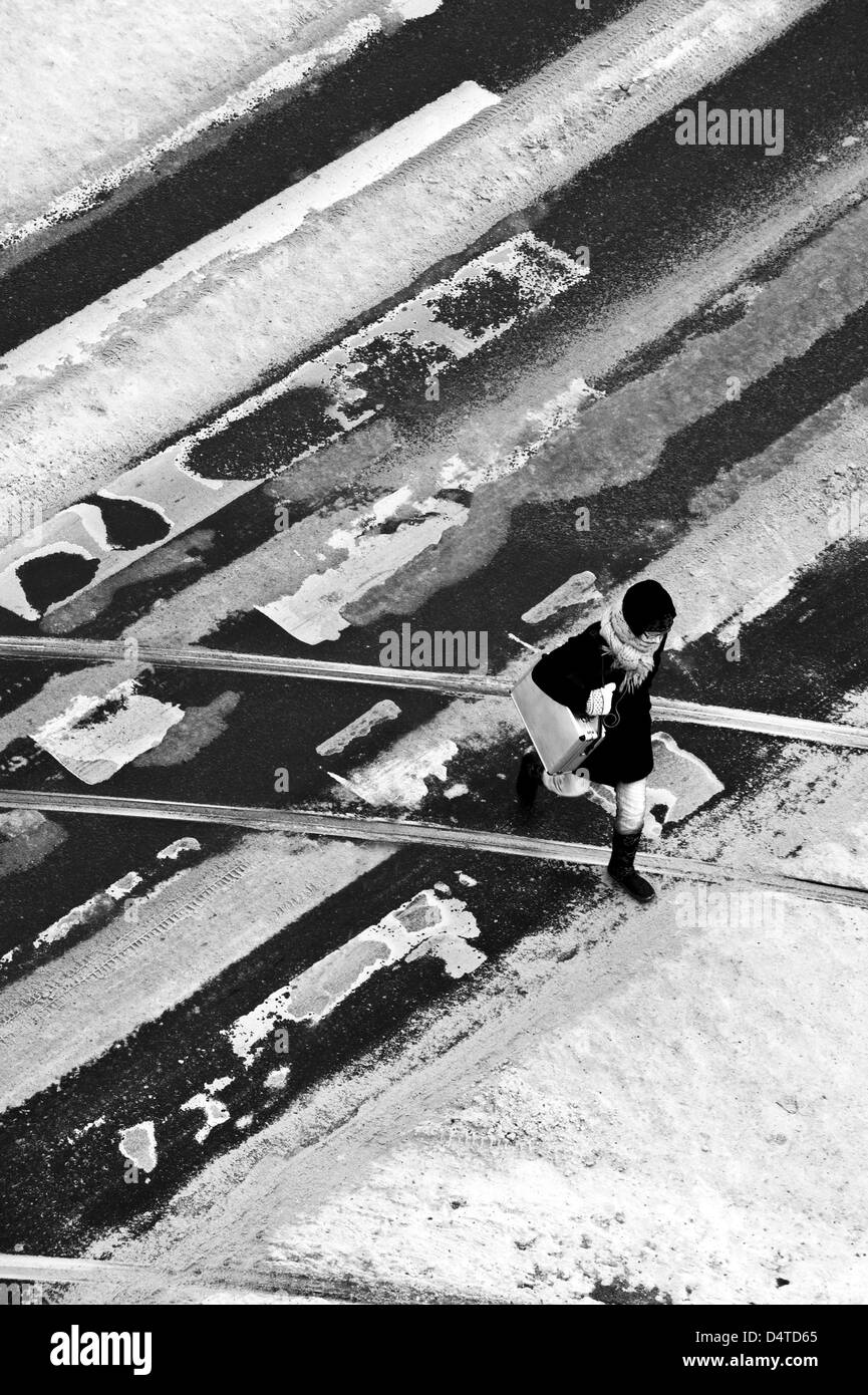 Donna che attraversa la strada a un percorso pedonale di attraversamento in inverno Foto Stock