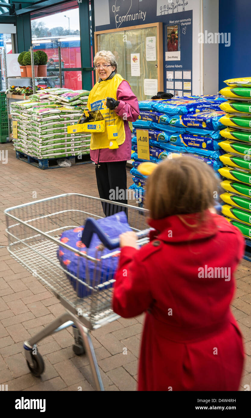 La donna la raccolta per le borse Marie Curie per la cura del cancro di carità nel piazzale del supermercato. Foto Stock