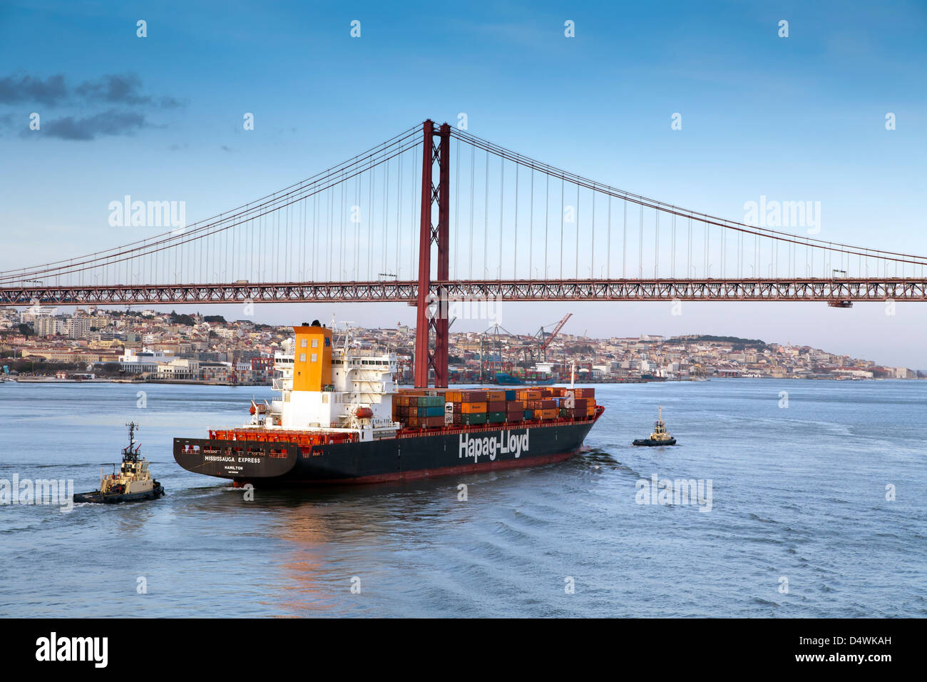 Lisbona, Portogallo. Una nave portacontainer con due rimorchiatori, teste per il ponte di Salazar. Chiamato anche 25APRILE Bridge e il Tago Foto Stock