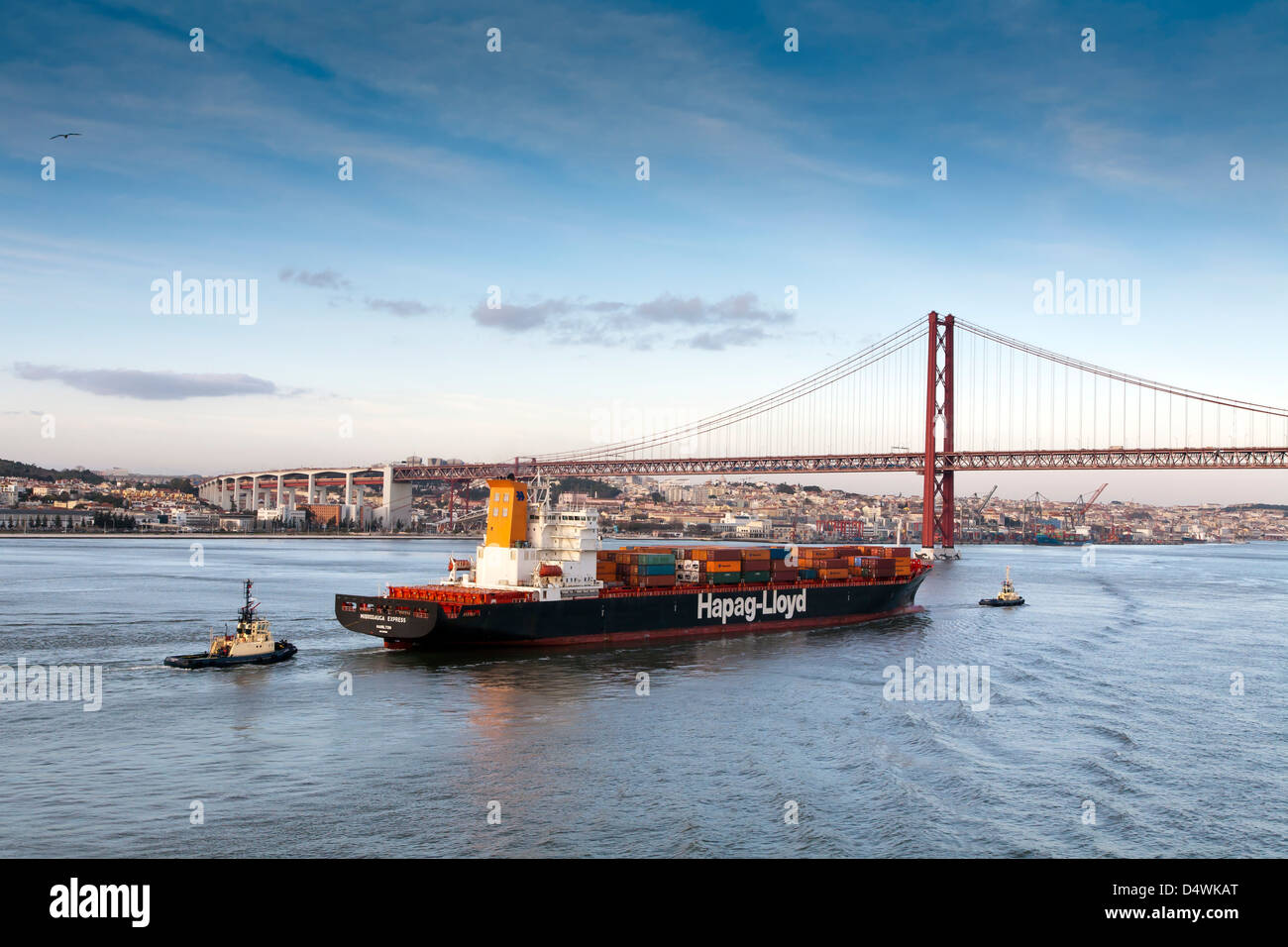 Lisbona, Portogallo. Una nave portacontainer con due rimorchiatori, teste per il ponte di Salazar. Chiamato anche 25APRILE Bridge e il Tago Foto Stock