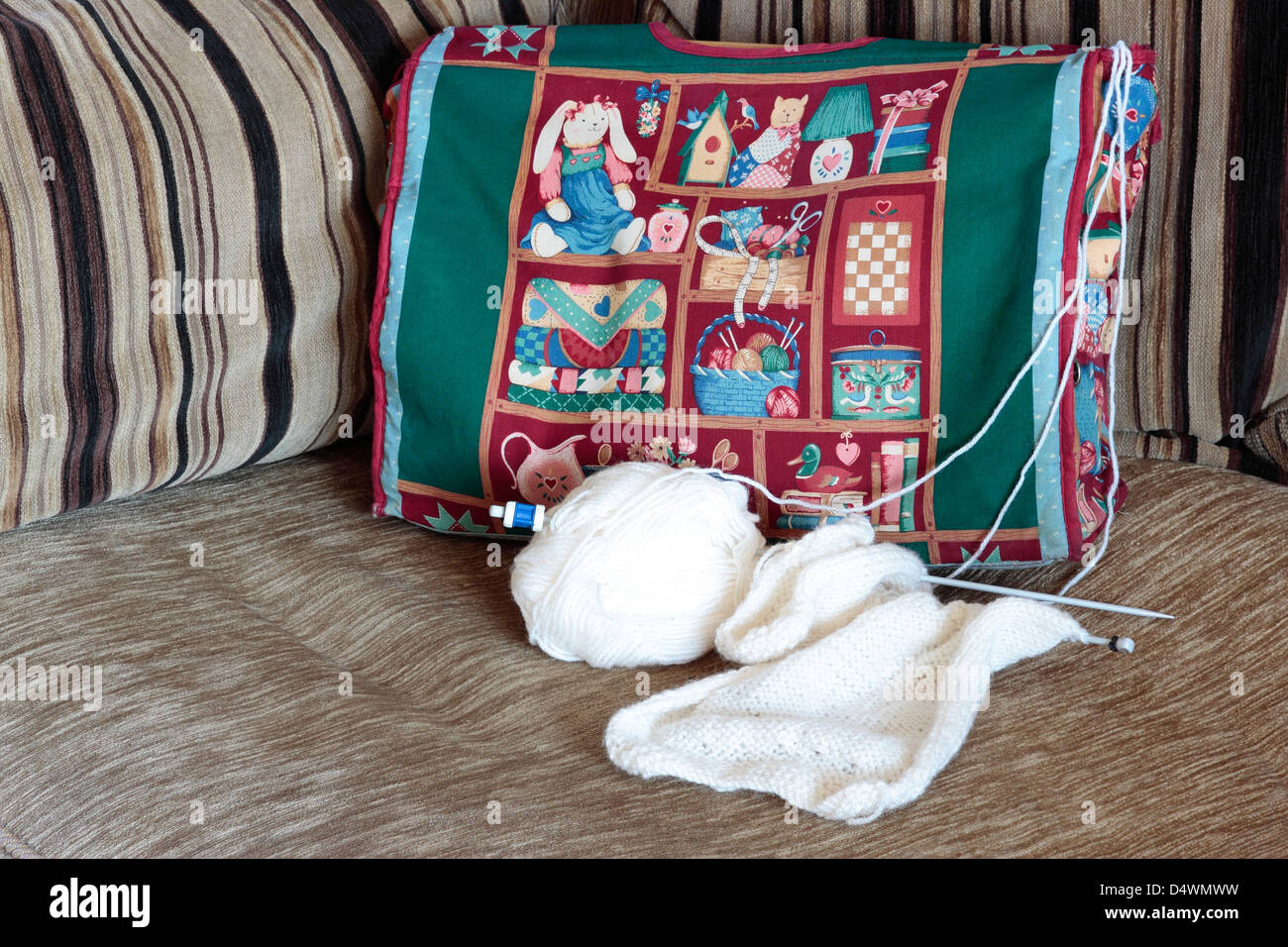 Un verde stampato maglia borsa sul divano con la parte finita cardigan bianco per un neonato Foto Stock