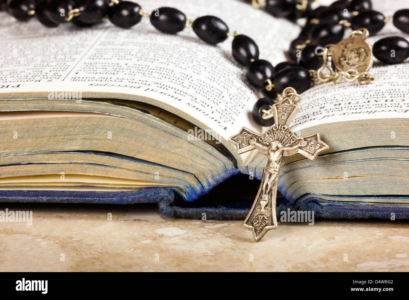 I grani del rosario e croce giacente su una pagina aperta della bibbia. Foto Stock