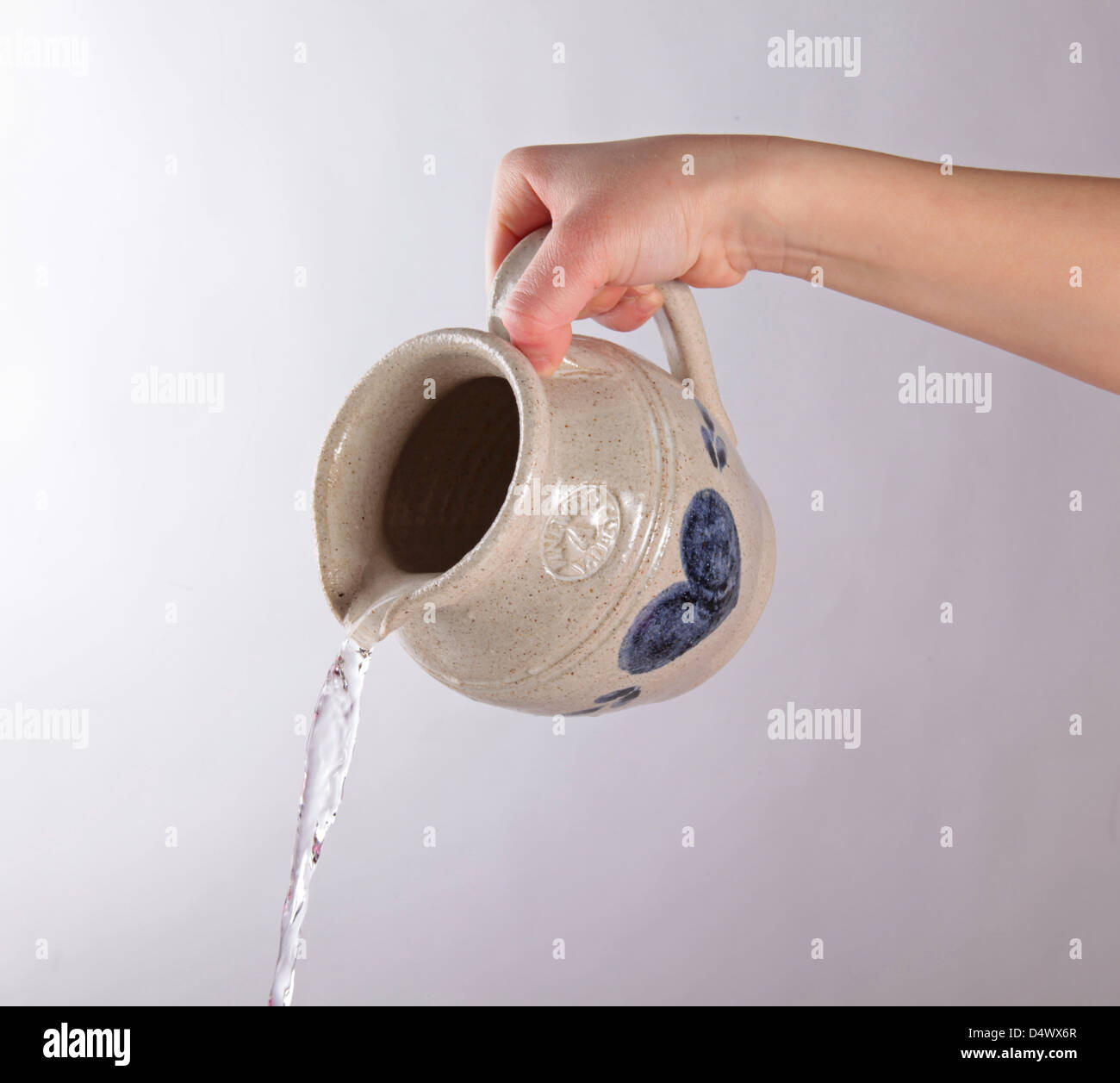 Ragazza irrigazione a mano con ceramica brocca da acqua isolato su sfondo bianco Foto Stock