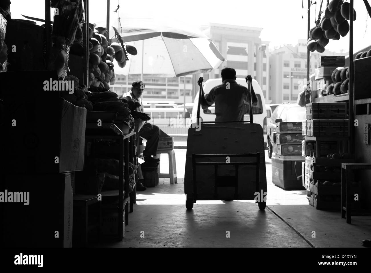 Silhouette di uomo tirando il carrello al mercato in Dubai Emirati Arabi Uniti Foto Stock