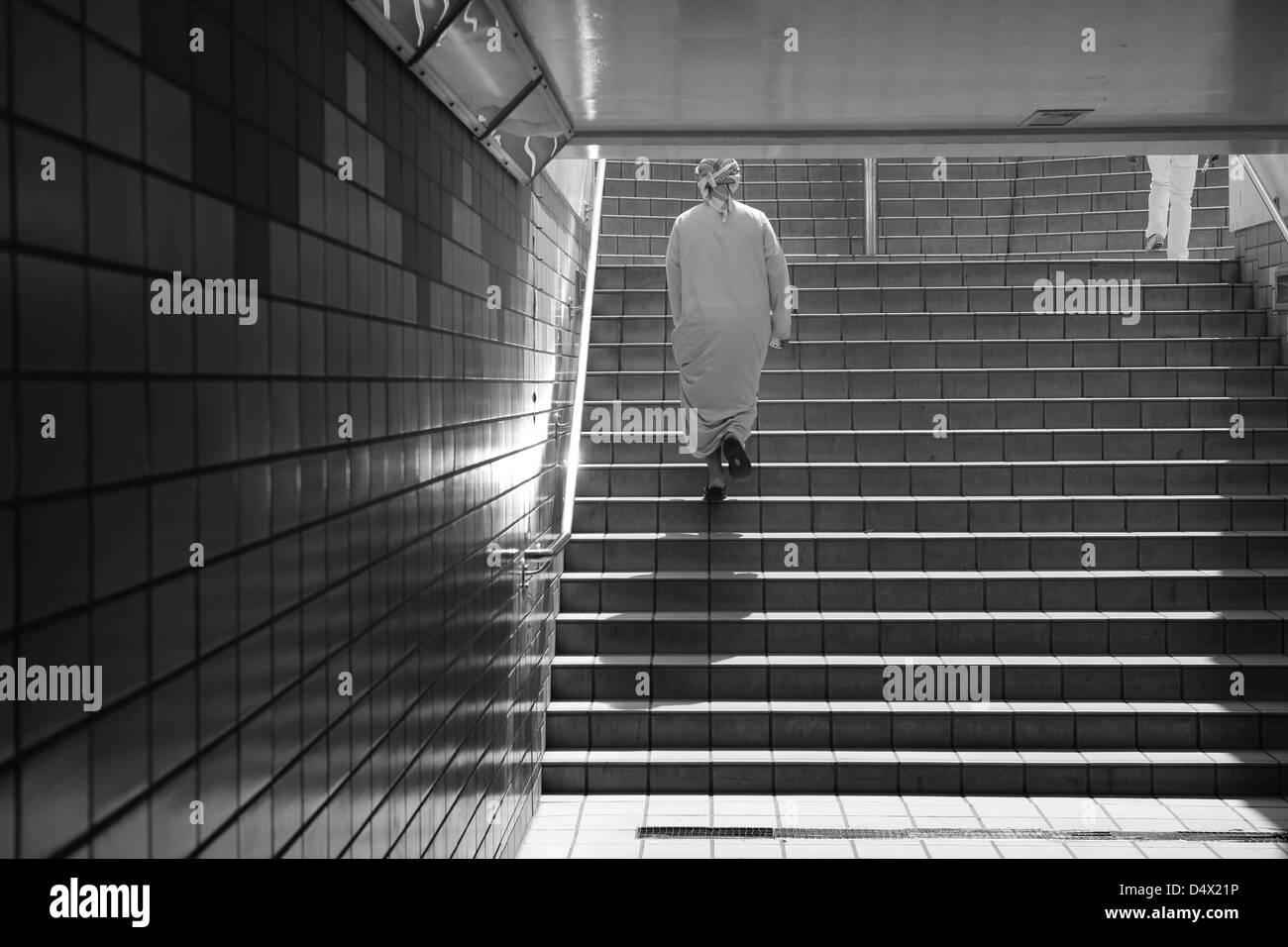 Uomo che cammina su per le scale dal passaggio pedonale sotterraneo, Dubai, Emirati Arabi Uniti Foto Stock