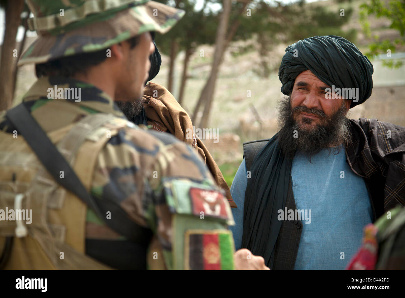 L Esercito nazionale afgano Forze Speciali soldato colloqui con un anziano locale durante una Shura riunione del Consiglio 19 marzo 2013 nella provincia di Helmand, Afghanistan. La shura era tenuto a decidere chi avrebbe il comando afghana per la polizia locale nella zona. Foto Stock