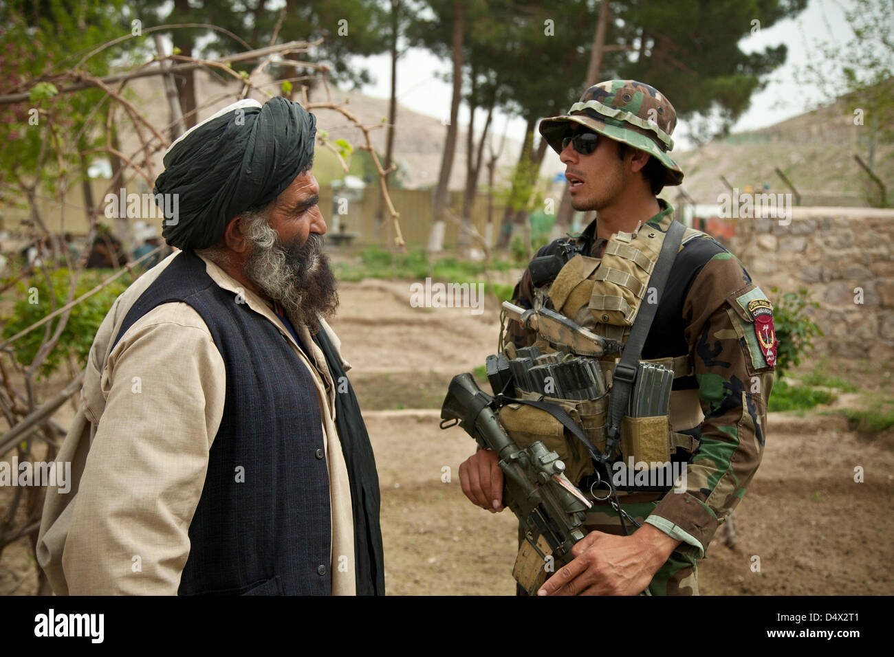 L Esercito nazionale afgano Forze Speciali soldato colloqui con un anziano locale durante una Shura riunione del Consiglio 19 marzo 2013 nella provincia di Helmand, Afghanistan. La shura era tenuto a decidere chi avrebbe il comando afghana per la polizia locale nella zona. Foto Stock