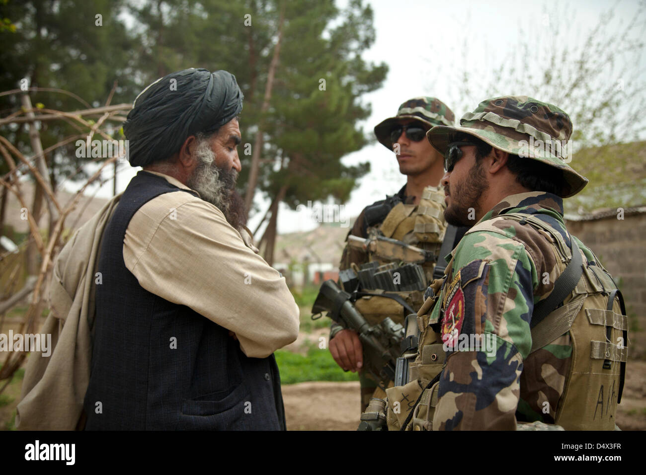 L Esercito nazionale afgano forze speciali militari parla con un anziano locale durante una Shura riunione del Consiglio 19 marzo 2013 nella provincia di Helmand, Afghanistan. La shura era tenuto a decidere chi avrebbe il comando afghana per la polizia locale nella zona. Foto Stock
