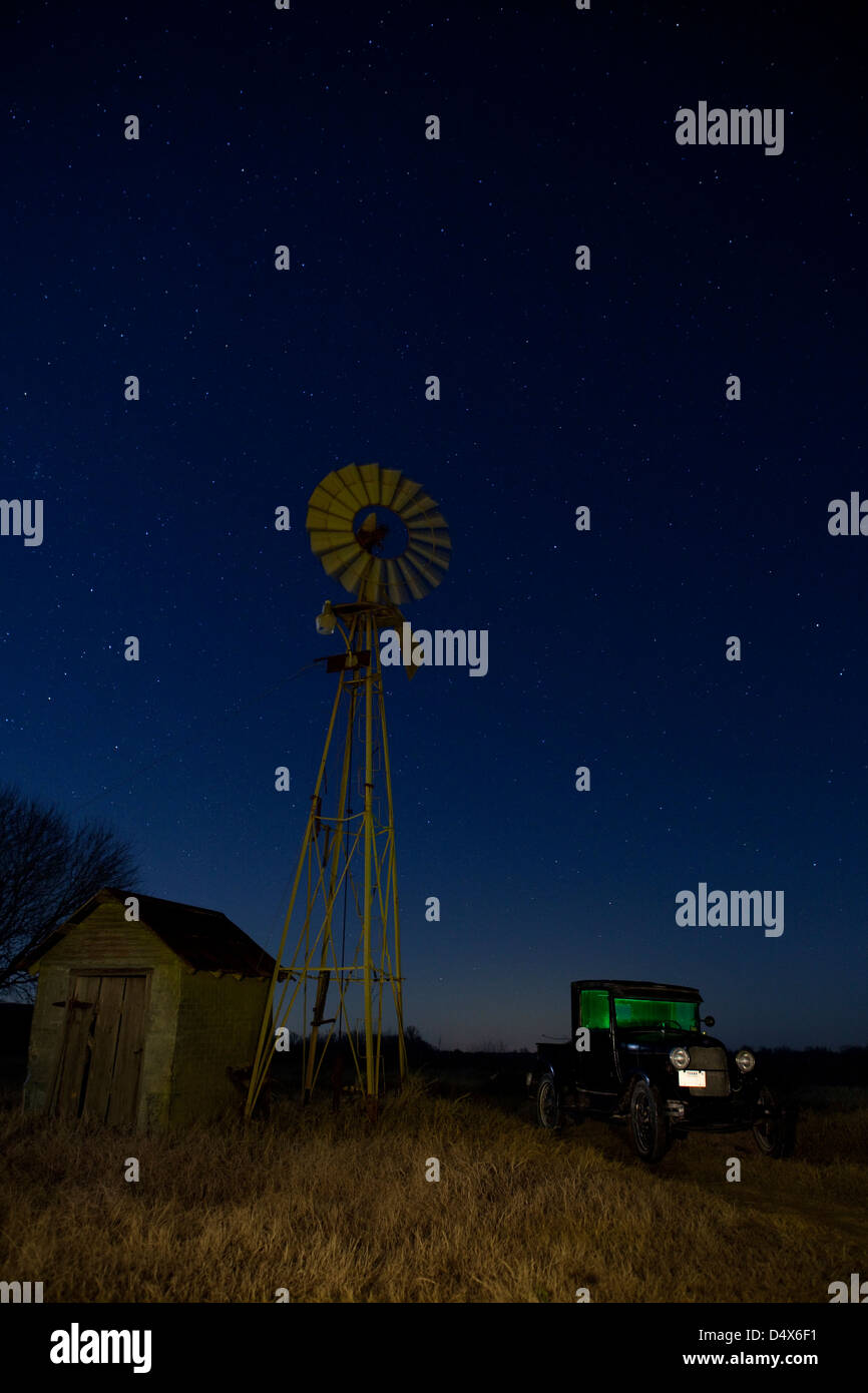 Vecchio modello T Farm carrello e il mulino a vento in una fattoria di notte in Texas, Stati Uniti d'America Foto Stock