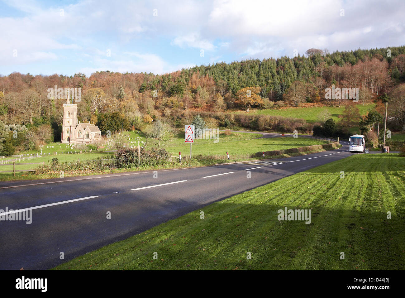 Un Webber autobus che viaggia lungo la A39 a west Quantoxhead, Somerset in Inghilterra con San Etheldreda della Chiesa la distanza Foto Stock