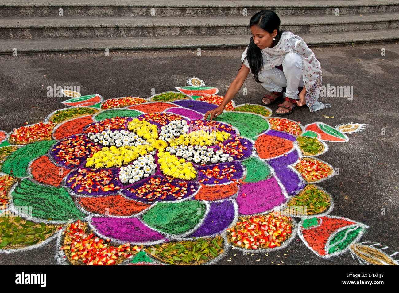 Chennai donna sta compiendo un Rangoli design con fiori in un Indiano street durante il festival indù di Sankranthi India India Foto Stock