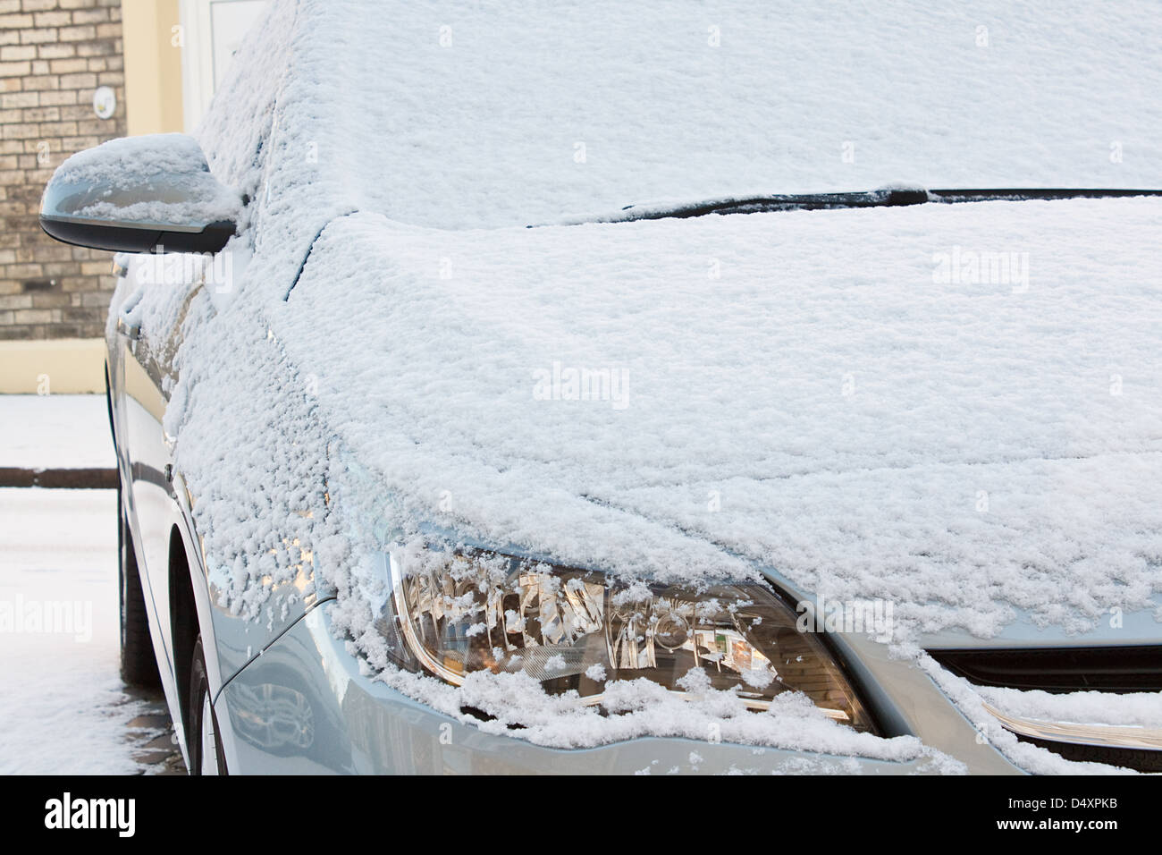 Il cofano anteriore e le luci delle auto europee rivestita di uno strato di neve fresca durante una dura stagione invernale Foto Stock