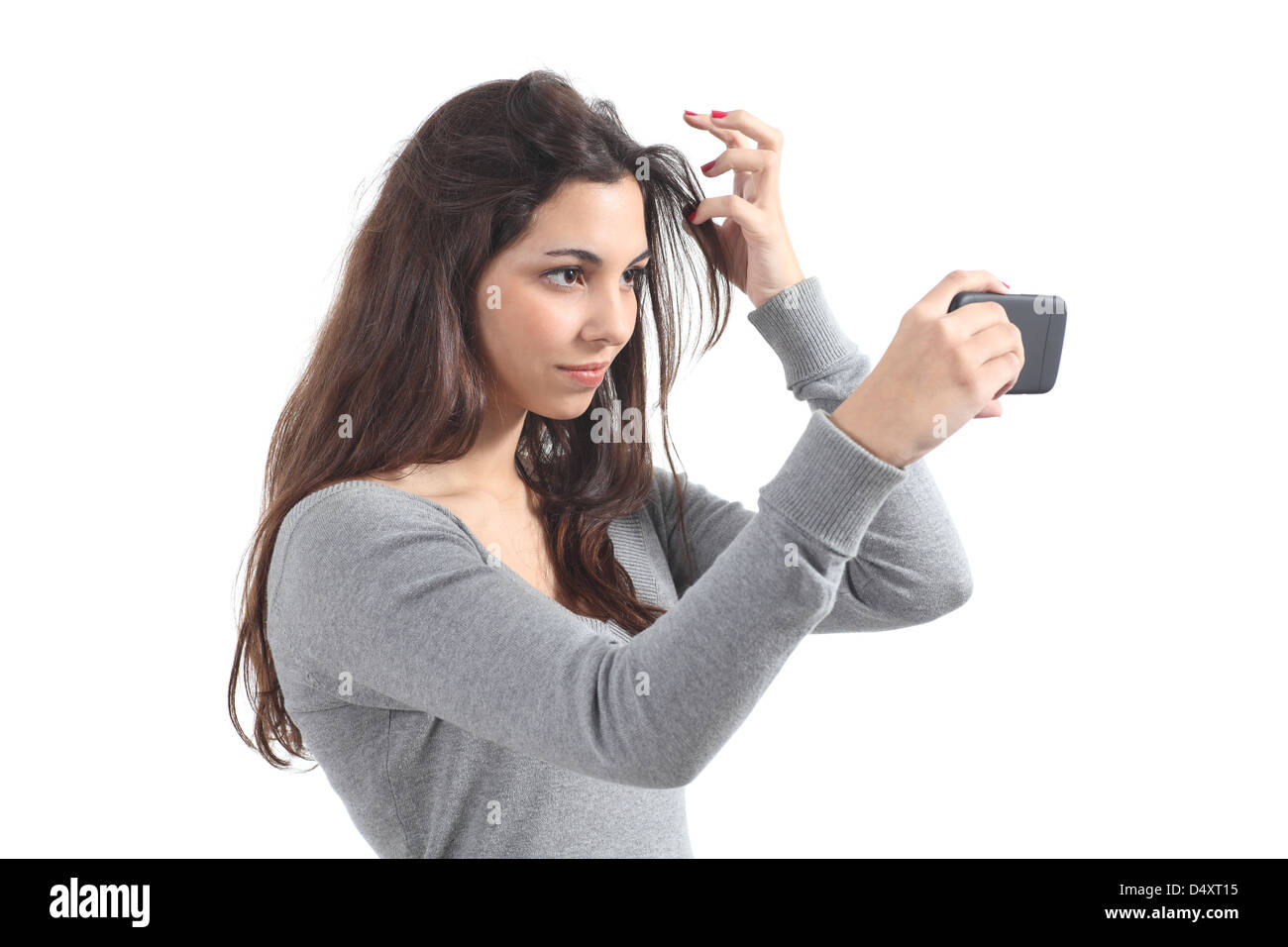 Bella adolescente primping i capelli utilizzando il suo telefono come uno specchio Foto Stock