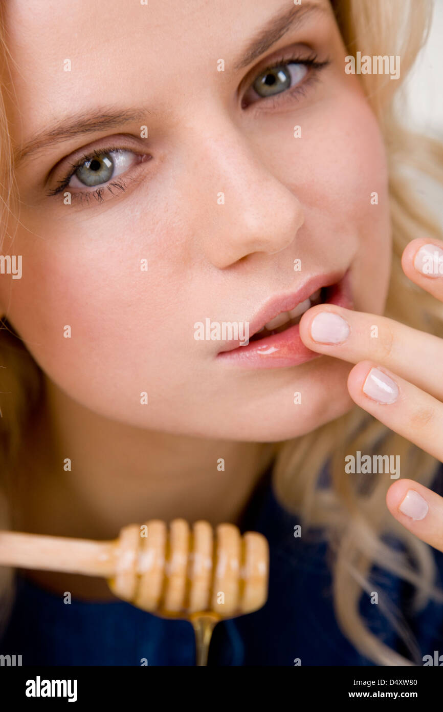 Donna mettendo il miele sulle labbra Foto Stock