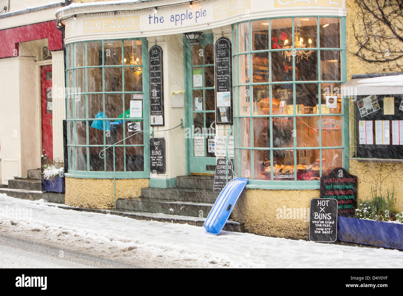 Una slitta al di fuori di un panificio a neve, Ambleside, Lake District, UK. Foto Stock