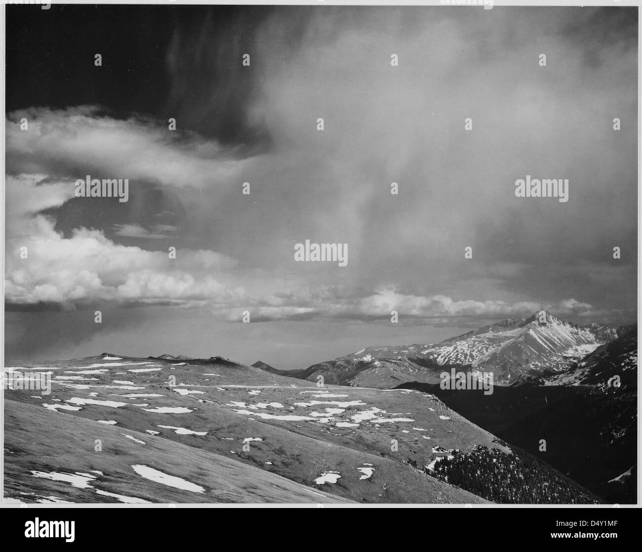 Una fotografia in bianco e nero delle vette del Rocky Mountain National Park, Colorado, scattata dal famoso fotografo Ansel Adams. L'immagine mostra nuvole sospese, un orizzonte suggestivo e paesaggi aspri, conservati dagli Archivi nazionali e dal National Park Service degli Stati Uniti. Foto Stock