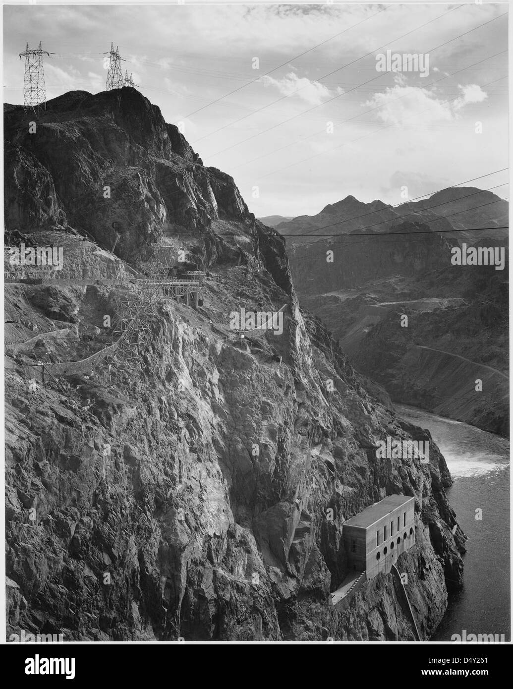 Una fotografia di Ansel Adams mostra le linee di trasmissione della diga di Boulder sopra il fiume Colorado e il Black Canyon. L'immagine, in bianco e nero, mette in risalto lo stile art deco della diga di Hoover e il suo significato ingegneristico. Preso come parte di un progetto del National Park Service degli Stati Uniti, mette in mostra le caratteristiche iconiche di questo monumento. Foto Stock