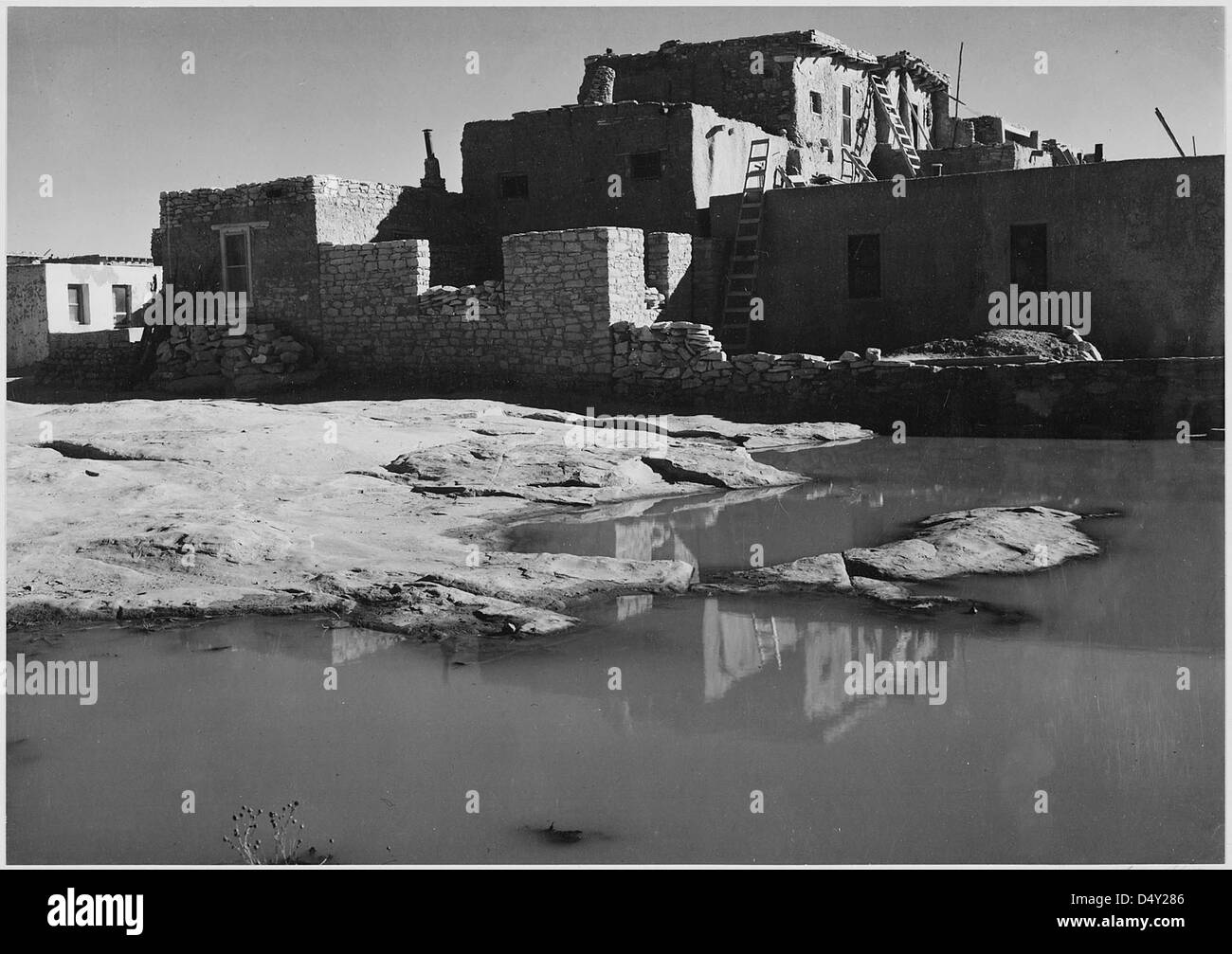 Una fotografia che mostra una vista laterale di una casa in adobe ad Acoma Pueblo nel New Mexico, un punto di riferimento storico nazionale. L'immagine cattura l'architettura e il paesaggio unici della zona. Foto Stock