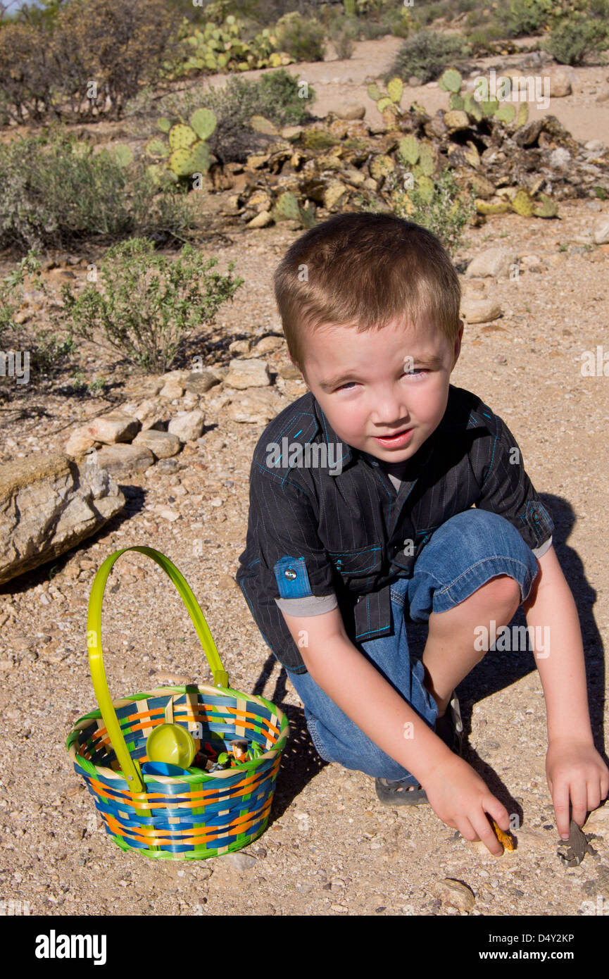 Un bambino di cinque anni, ragazzo con autismo si prende una pausa dalla caccia per uova in plastica per giocare con il suo nuovo animale giocattoli. Foto Stock