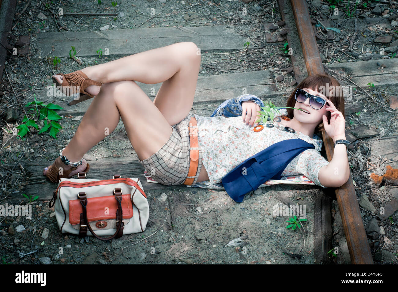 Il giovane bella ragazza giace su rusty le vie della stazione Foto Stock