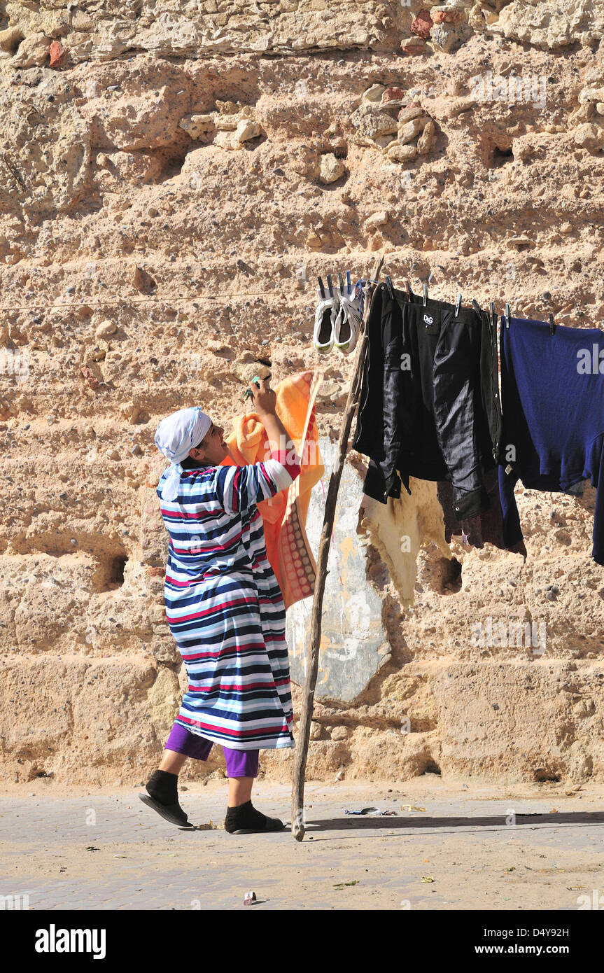 Casalinga marocchina che appende il lavaggio domestico su una linea di vestiti all'interno delle mura fortificate della città di Essaouira, Marocco Foto Stock