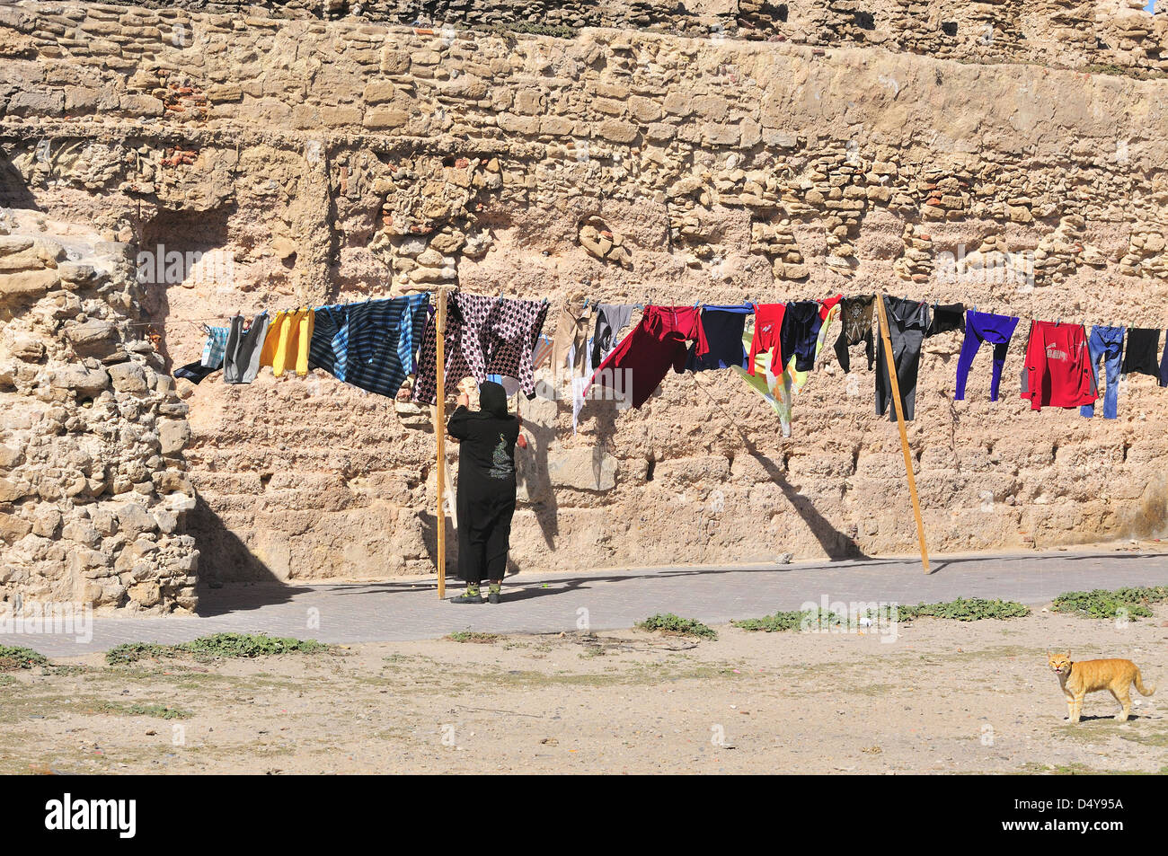 Casalinga marocchina che appende il lavaggio domestico su una linea di vestiti all'interno delle mura fortificate della città di Essaouira, Marocco Foto Stock