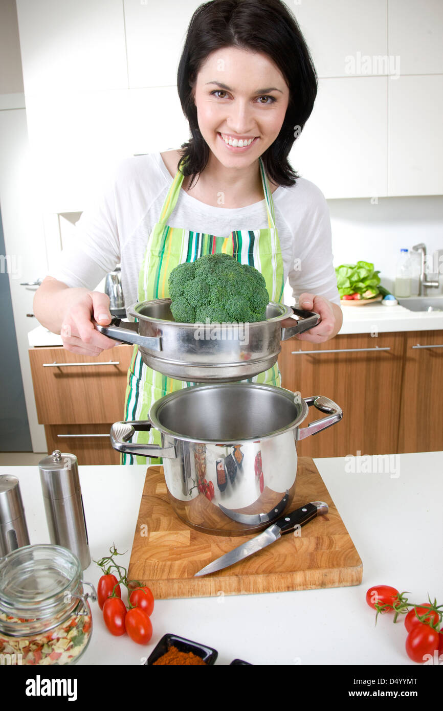 Donna della cottura a vapore i broccoli Foto Stock