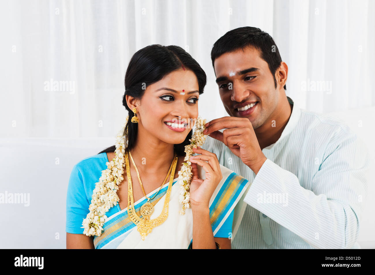 Sud indiane uomo mettendo gajra nelle sue mogli capelli Foto Stock
