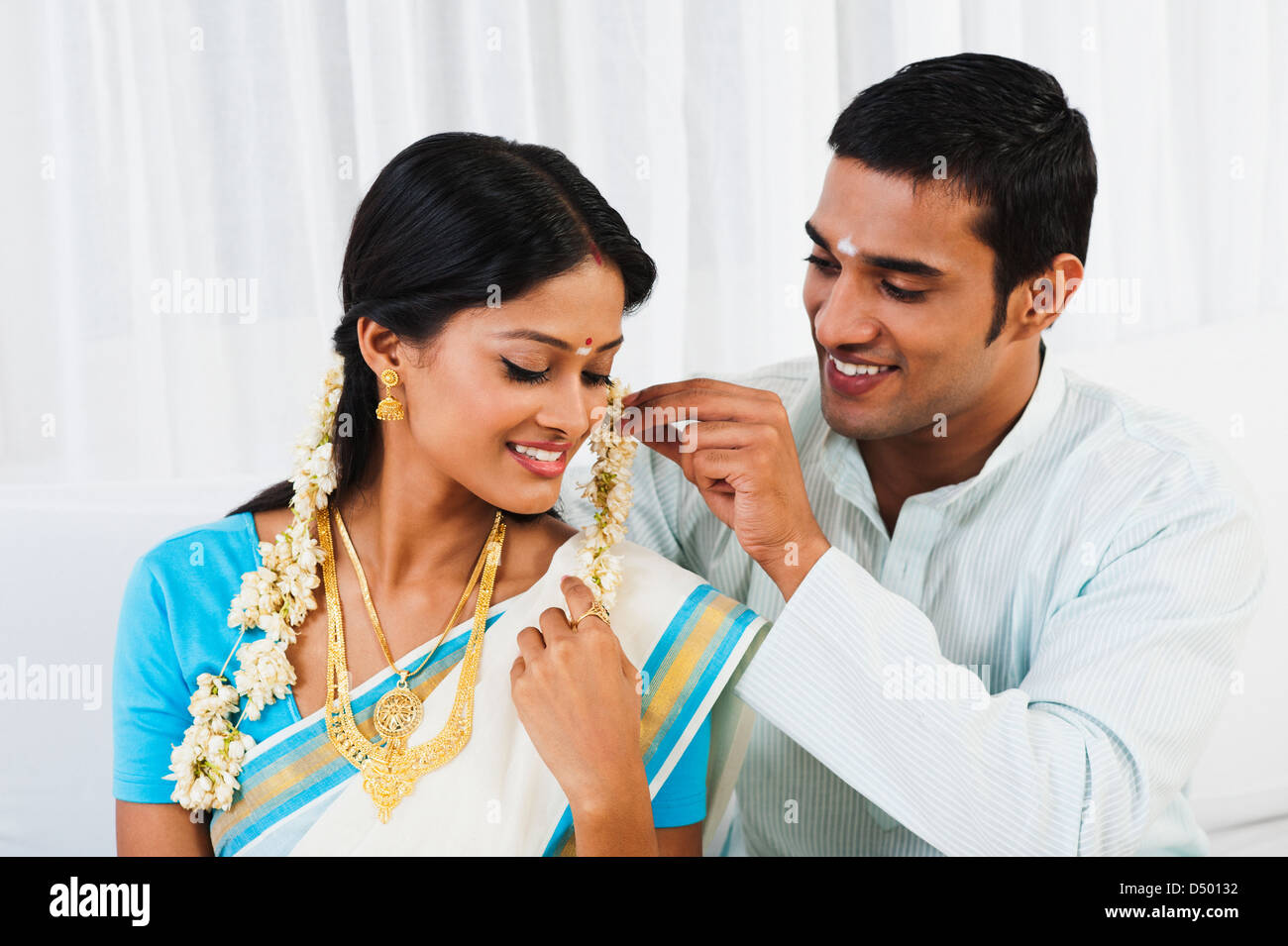 Sud indiane uomo mettendo gajra nelle sue mogli capelli Foto Stock