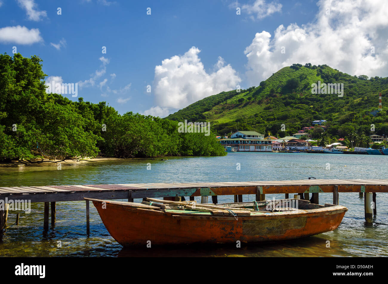 Vecchi e consunti barca e dock con isola tropicale in background Foto Stock