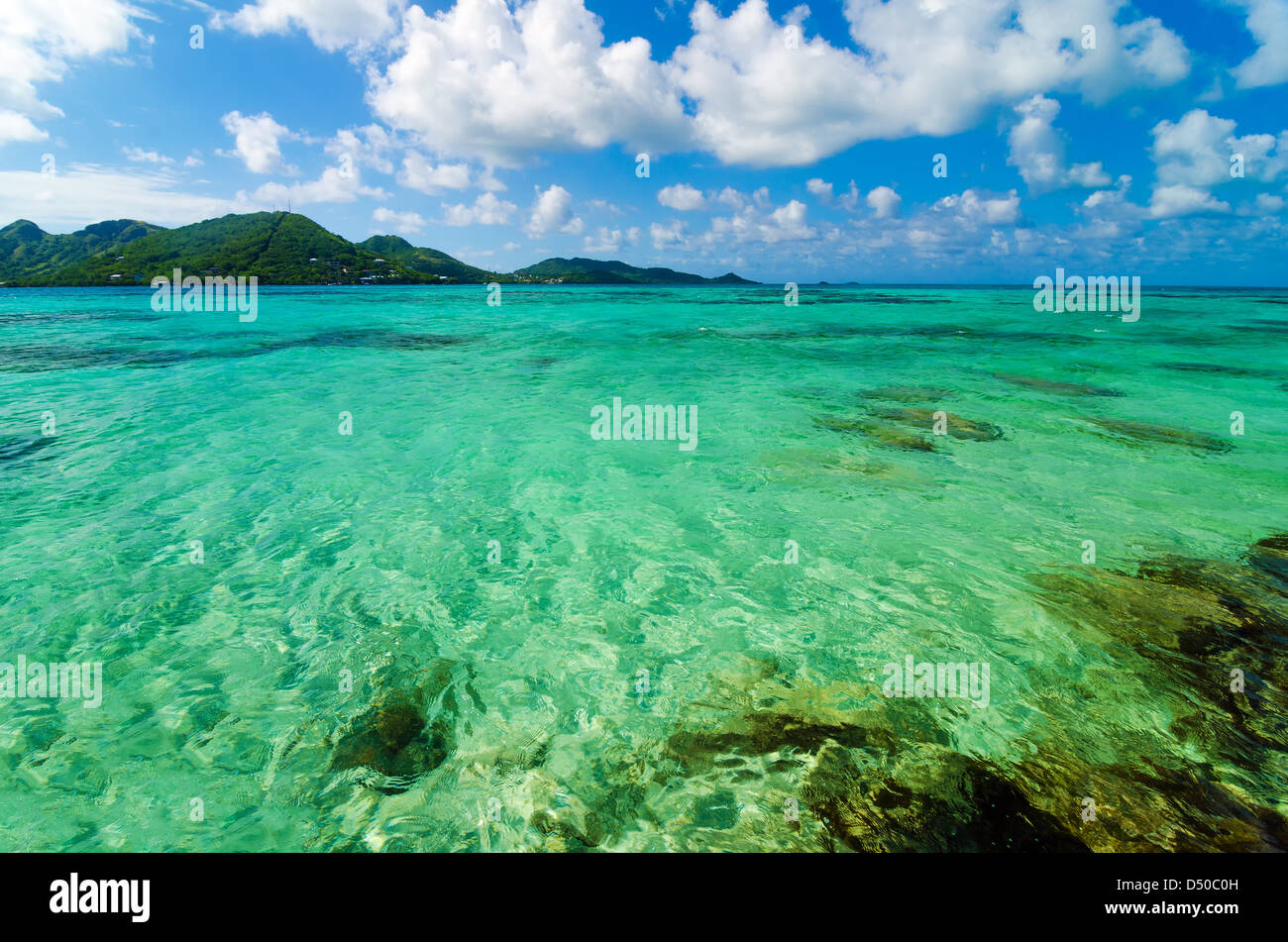 Bellissimi Caraibi turchesi acqua di mare con un isola tropicale in background Foto Stock