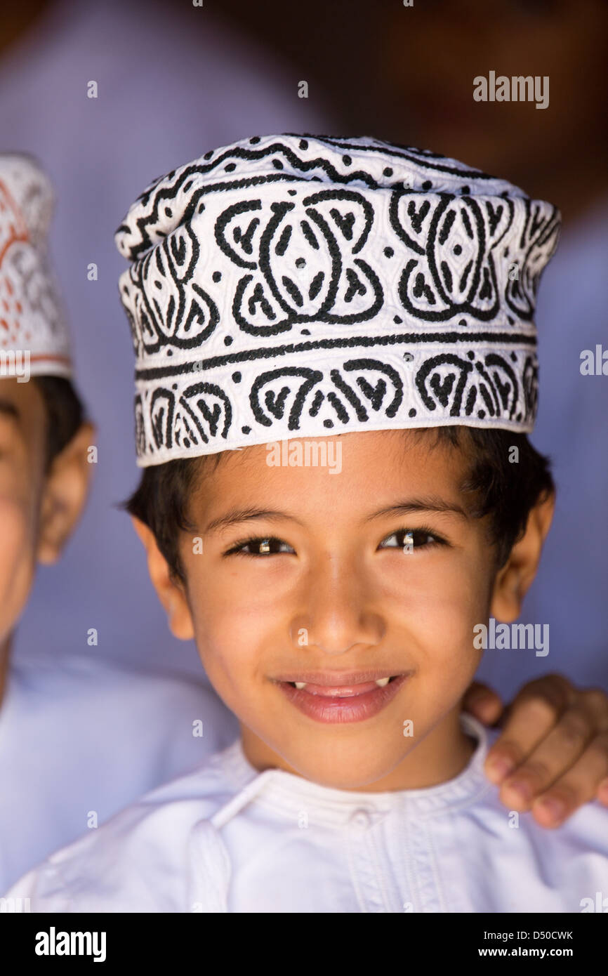 Un Omani scolaro in un piatto bianco dash indossando un cappello tradizionale o copricapo Foto Stock