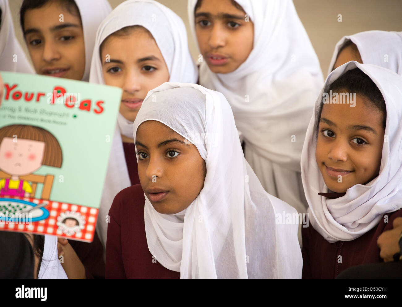 Omani ragazze della scuola nel copricapo di apprendimento della lingua inglese a una lezione di lettura in una scuola di ragazze in Campidoglio di Oman, Doha. Foto Stock