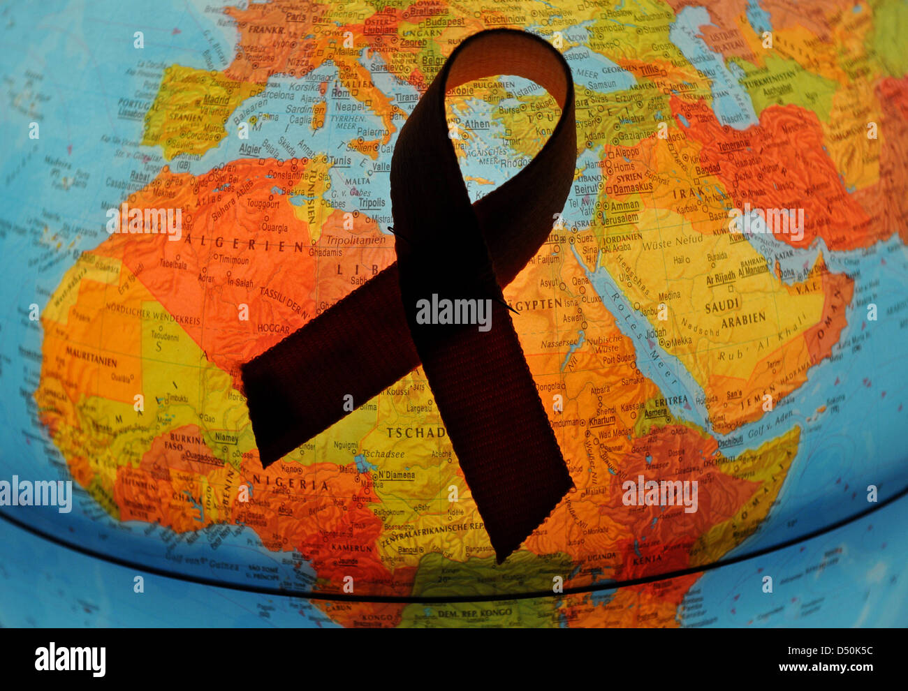 Un rosso nastro aids giace su un globo a Francoforte sull'Oder, Germania, 29 novembre 2010. L Organizzazione Mondiale della Sanità ha proclamato il 1 dicembre come Giornata mondiale di lotta all Aids dal 1988. In tutto il mondo, le organizzazioni ricordare al pubblico che l'Aids è ancora un grave problema e chiamata a prendere provvedimenti e a manifestare solidarietà con infettati da HIV e le persone affette da AIDS e con i loro amici e Foto Stock