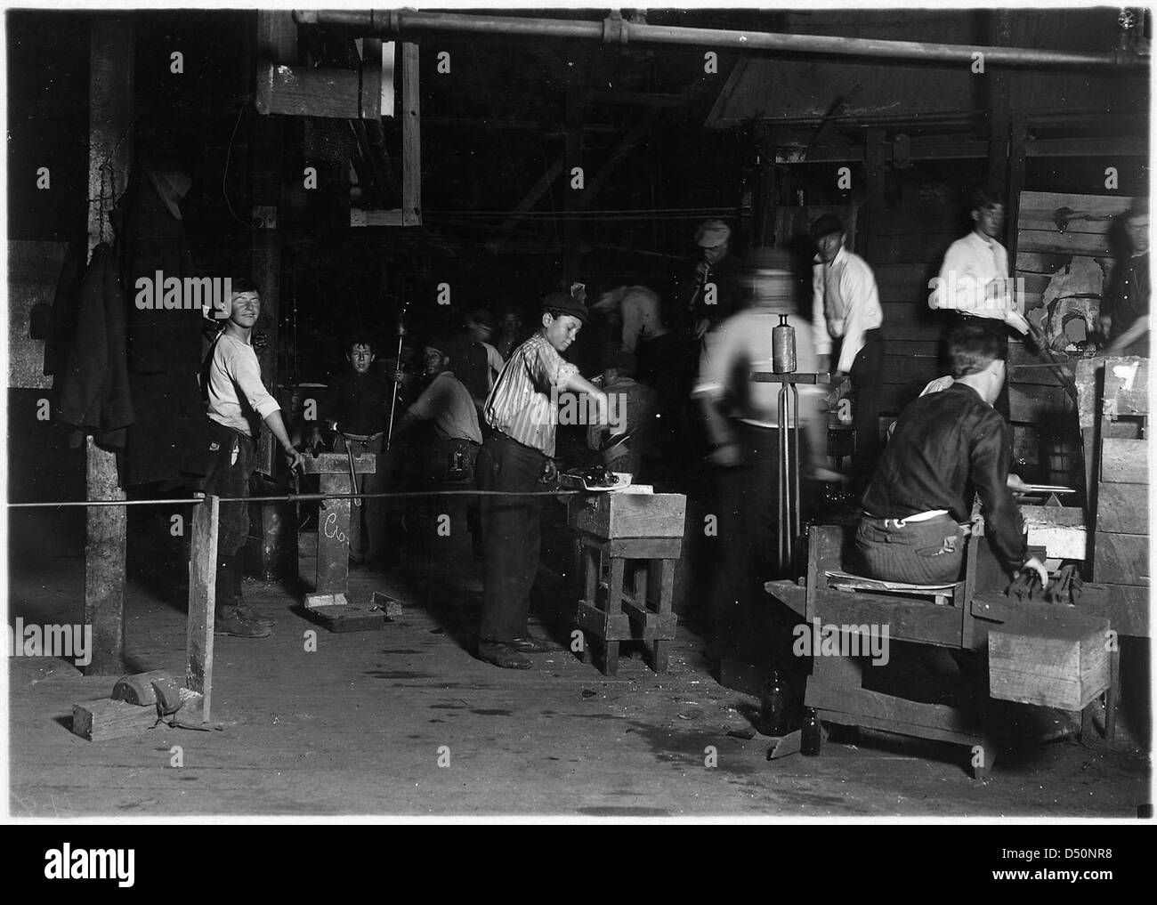 Questa fotografia del 1909 di Lewis Hine raffigura il turno di notte alla Cumberland Glass Works di Bridgeton, New Jersey, mostrando le dure condizioni di lavoro affrontate dai lavoratori, in particolare dai bambini, durante l'inizio del XX secolo. Foto Stock