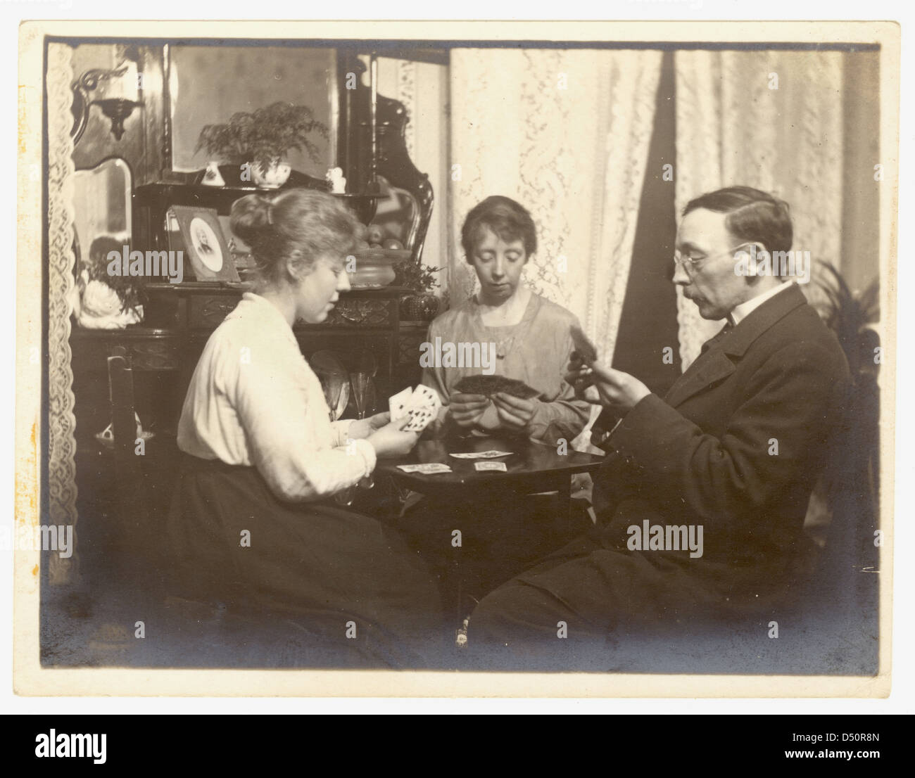 Fotografia del gruppo eduardiano carte da gioco nel loro salotto. In vecchio stile Edwardian i passatempi, U.K. Foto Stock