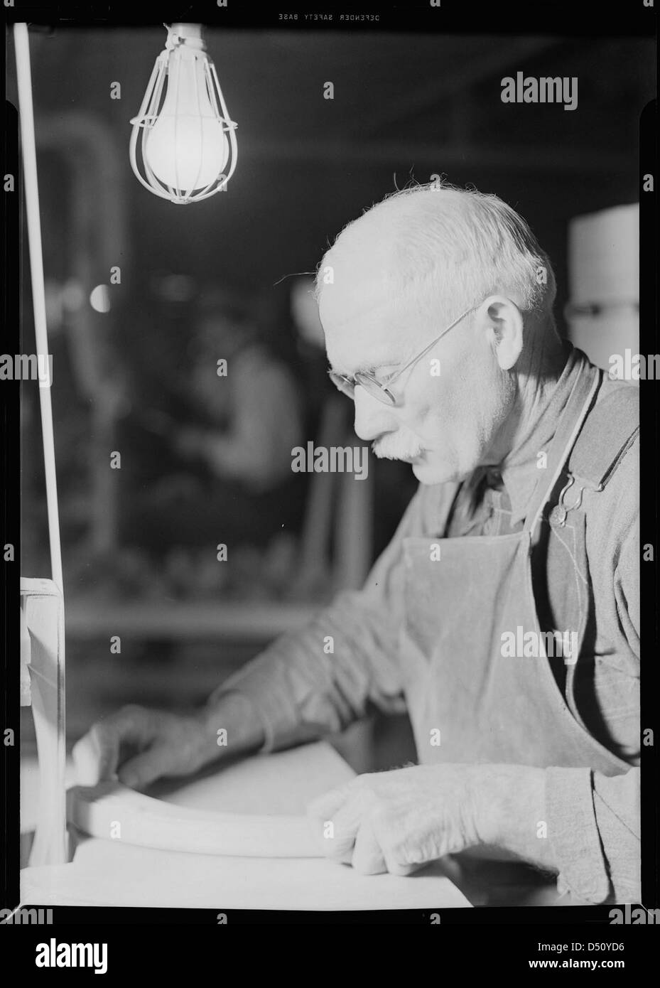 Un lavoratore della Tomlinson Chair Manufacturing Co. Di High Point, North Carolina, utilizza una levigatrice a nastro verticale su un braccio per sedia nel 1936. Questa immagine riflette il lavoro nell'industria del mobile durante la grande depressione. Foto Stock