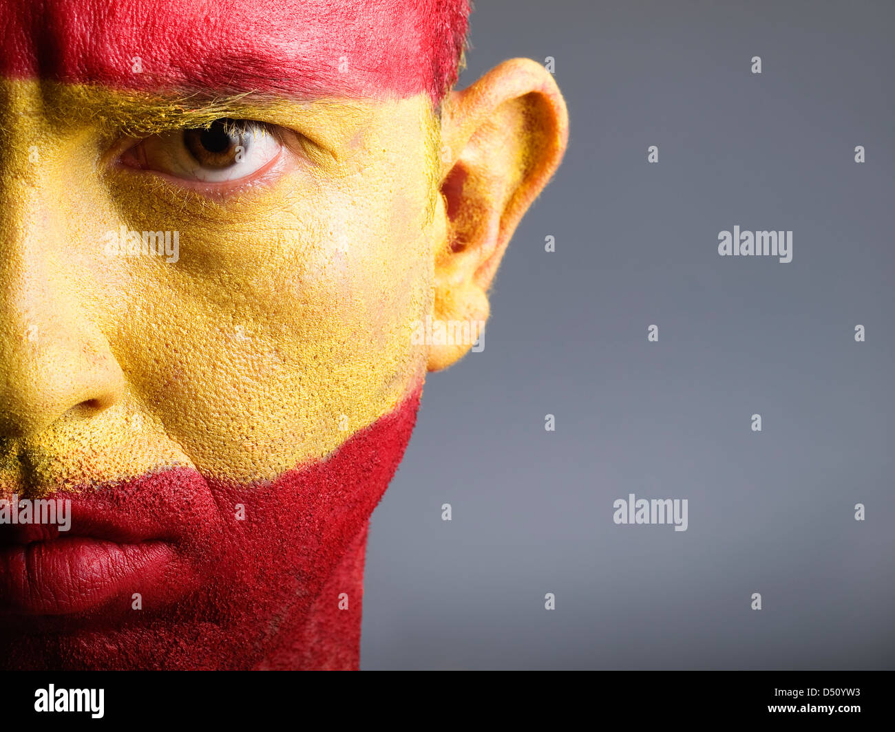 L'uomo con il suo volto dipinto con la bandiera della Spagna. L'uomo è grave e composizione fotografica lascia solo metà della faccia. Foto Stock